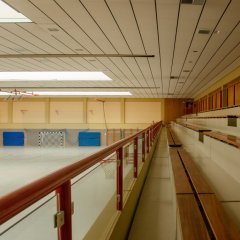 auf der rechten Seite lange Holzbänke und auf der linken Seite Hallenboden mit einem Handballtor