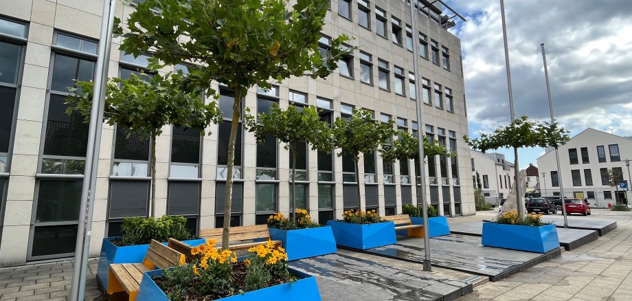 Blaue Pflanzübel mit Dachplatenen vor dem Walldorfer Rathaus und Holzbänke