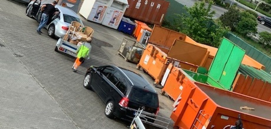 Werstoffhof Schlange von Autos mit Anhänger und dahinter offene Müllcontainer