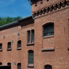 Rot geklinkter Bau mit Fenstern die mit Gittern vor den Fenstern.