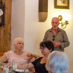 Drei Frauen im Vordergrund am Tisch sitzend und Herr J. Heise im Hintergrund stehend.