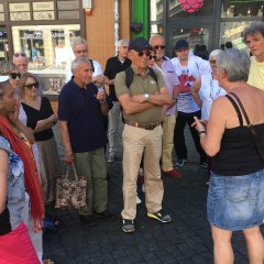 Bildungsfahrtteilnehmer vor Schaufenstern der alter Gebäude stehend.