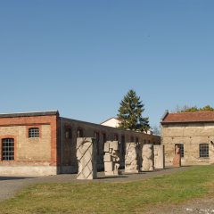 grüner und mit Kiesel versehener Appellplatz, umgeben von 2 Backsteinhäusern links und im Vordergrund des Platzes