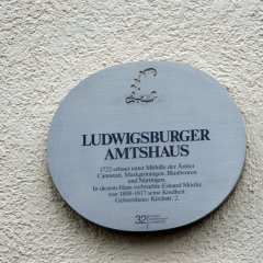 Rundes graues Schild an der Wand hängend mit der Aufschrift Ludwigsburger Amtshaus und weitere Informationen