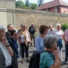 Bildungsfahrtteilnehmer im Innenhof der Zentralen Stelle vor einer alten Mauer stehend.