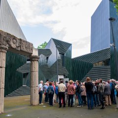 Die Bildungsfahrtteilnehmer stehen auf dem Haupteingang der neuen Synagoge und auf der linken Seite sind noch die alten Säulenreste der ehemaligen Synagoge zu sehen