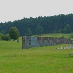 grüne Wiese mit alten Mauerresten und Kontrollturm