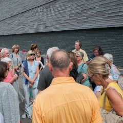 Bildungsfahrtteilnehmer vor der mit Namen in Stein versehenen Steinwand der Gedenkstätte