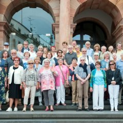 Gruppenbild der Bildungsfahrtteilnehmer auf der  großen Treppe vor dem gläsernen Eingang des Wiesbadener Rathauses