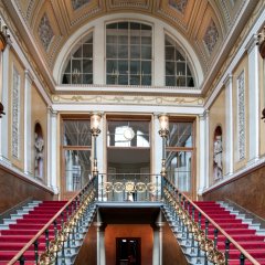 Rechts und links hinauf führende Treppen zum gläseren Eingang des historischen Schlosses