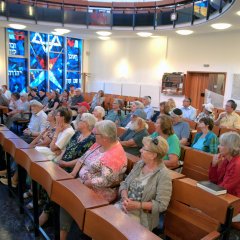 Bildungsfahrtteilnehmer im großen Saal der Synagoge in Bänken sitzend. 