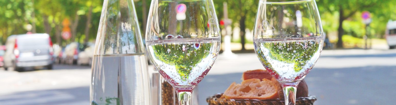 Zwei Wassergläser auf gedecktem Tisch in einem Straßencafe