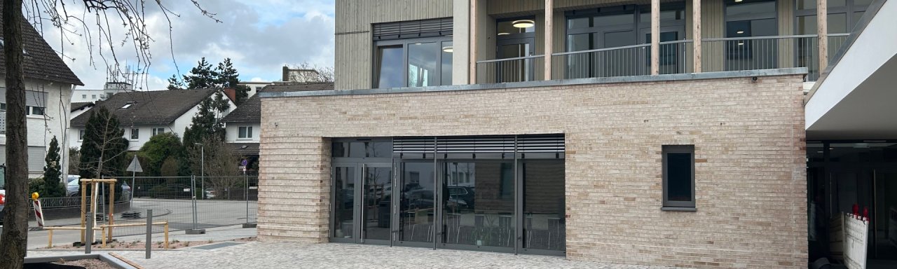 Bllick auf das dreistöckige terrassenförmige Gebäude vom gepflasterten Hof.