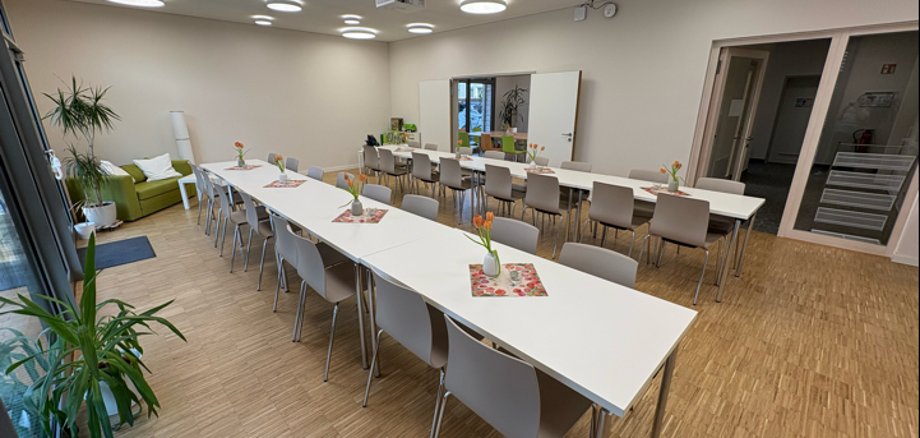 Heller Raum mit zwei langen Tischen und je 16 Plätzen daran.