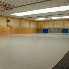 Hallenboden mit grünen, roten und schwarzen Markierungen und im Hintergrund die Hallenbegrenzung mit einer Wand