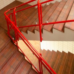braune geflieste Treppenstufen mit roten Handlauf