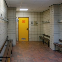 weiß gefliester Raum mit braunen Holzbänken an der rechten und der linken Wandseite