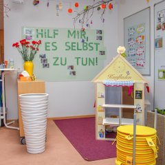 Ein Kaufladen steht hinter einem Stapel gelber Kissen.  Auf der linken Seite steht ein weißer Stehtisch.