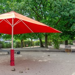 Roter Sonnenschirm im Sandkasten.