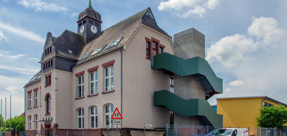 Altes Schulgebäude mit neuem Treppenaufgang an der Außenseite.