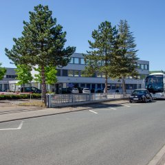Ansicht eines Bürogebäudes mit Bäumen im Vordergrund