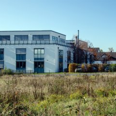 Bürogebäude auf der Opelstraße mit unbebautem, mit Gräsern bewachsenem Grundstück im Vordergrund