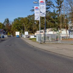 Straßenansicht eines Gewerbebetriebes mit wehenden Fahnen 