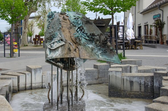 Figuren  zieren einen aus Bronze und Stelzen stehenden Brunnen