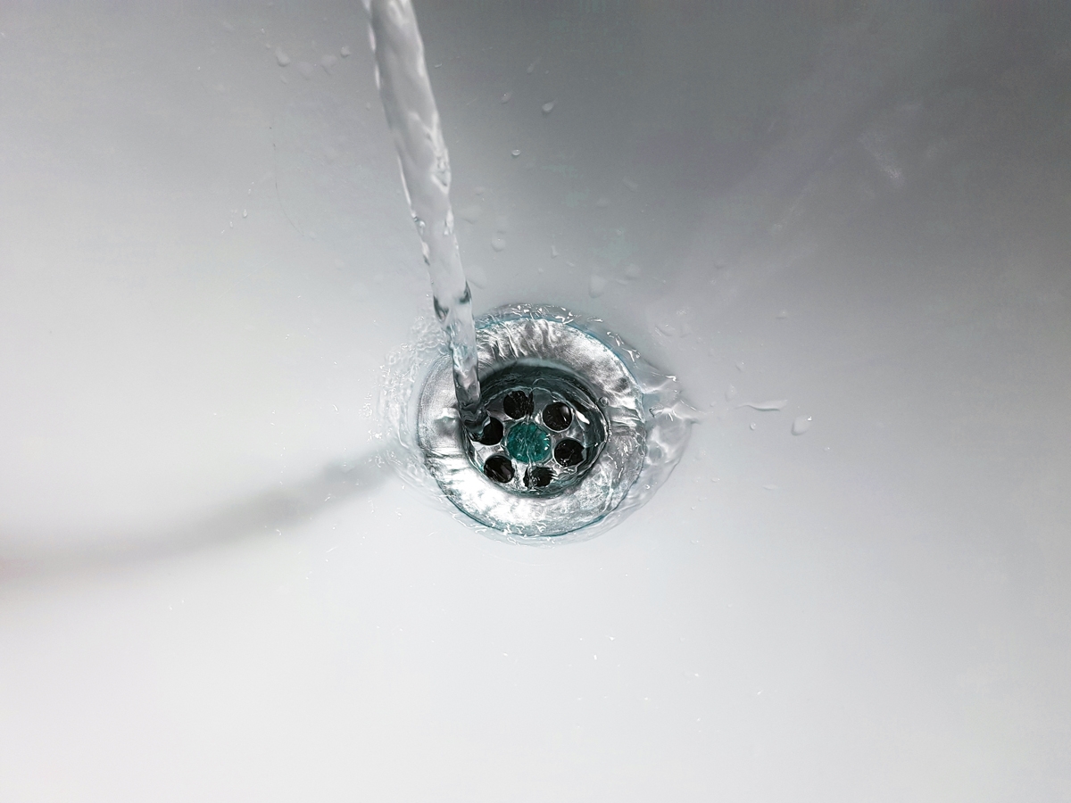 Wasser läuft in den Ausguss eines Waschbeckens