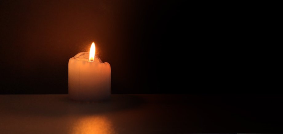 Eine kleine Kerze leuchtet in der Dunkelheit