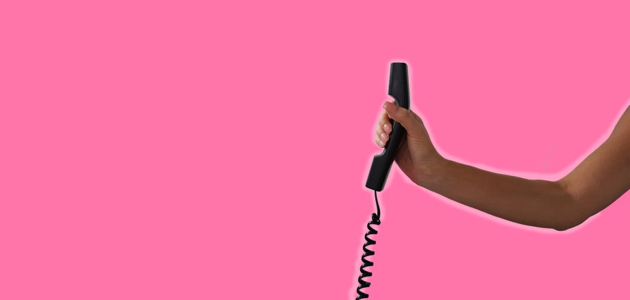 Eine Hand reicht den Telefonhörer 