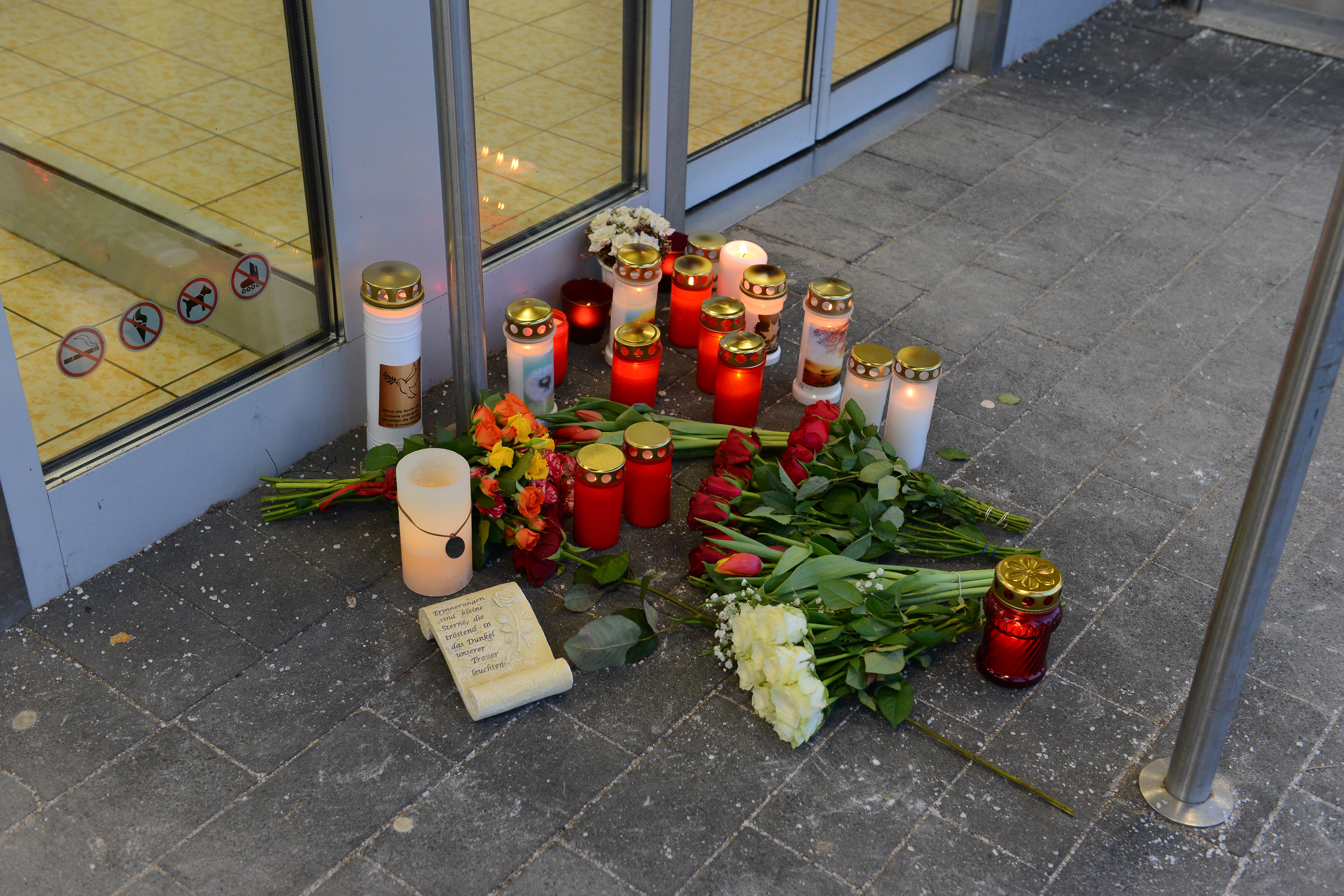 Brennende Kerzen und ein Blumenstrauß vor der Tür der Aldi-Filialie