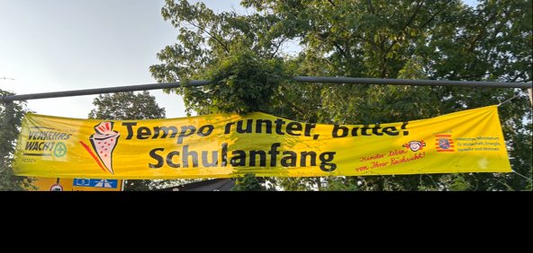 Das Banner mit der Aufschrift Tempo runter, Bitte, Schulanfänger hängt an 