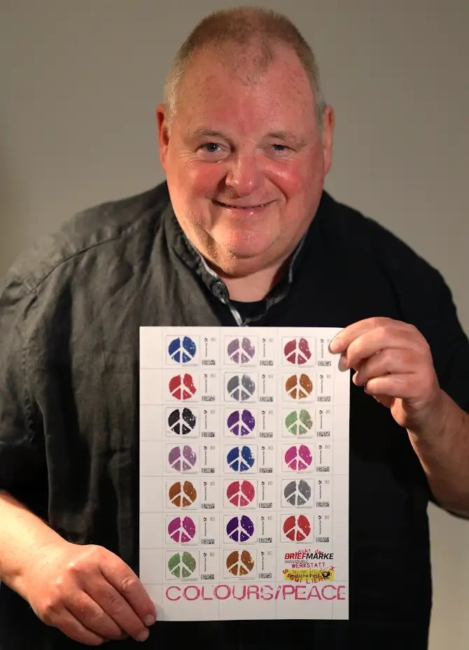 Siggi Liersch hält ein Bild mit den Briefmarken in der Hand