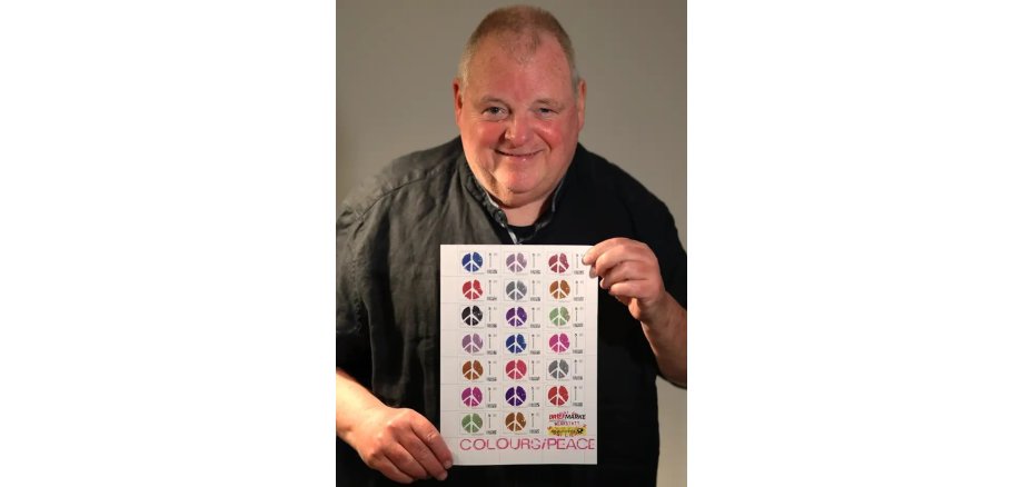 Siggi Liersch hält ein Bild mit den Briefmarken in der Hand