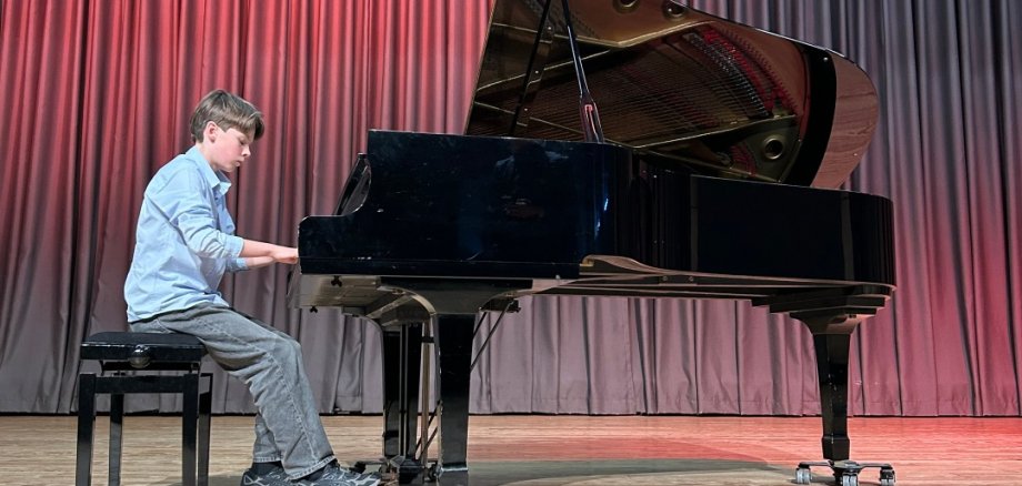 Bürgermeister Karsten Groß und Preisträger Jonas Rahn schauen gut gelaunt in die Kamera, Jonas hält eine Urkunde in der Hand. Der Bürgermeister schüttelt die Hand von Jonas zur Gratulation