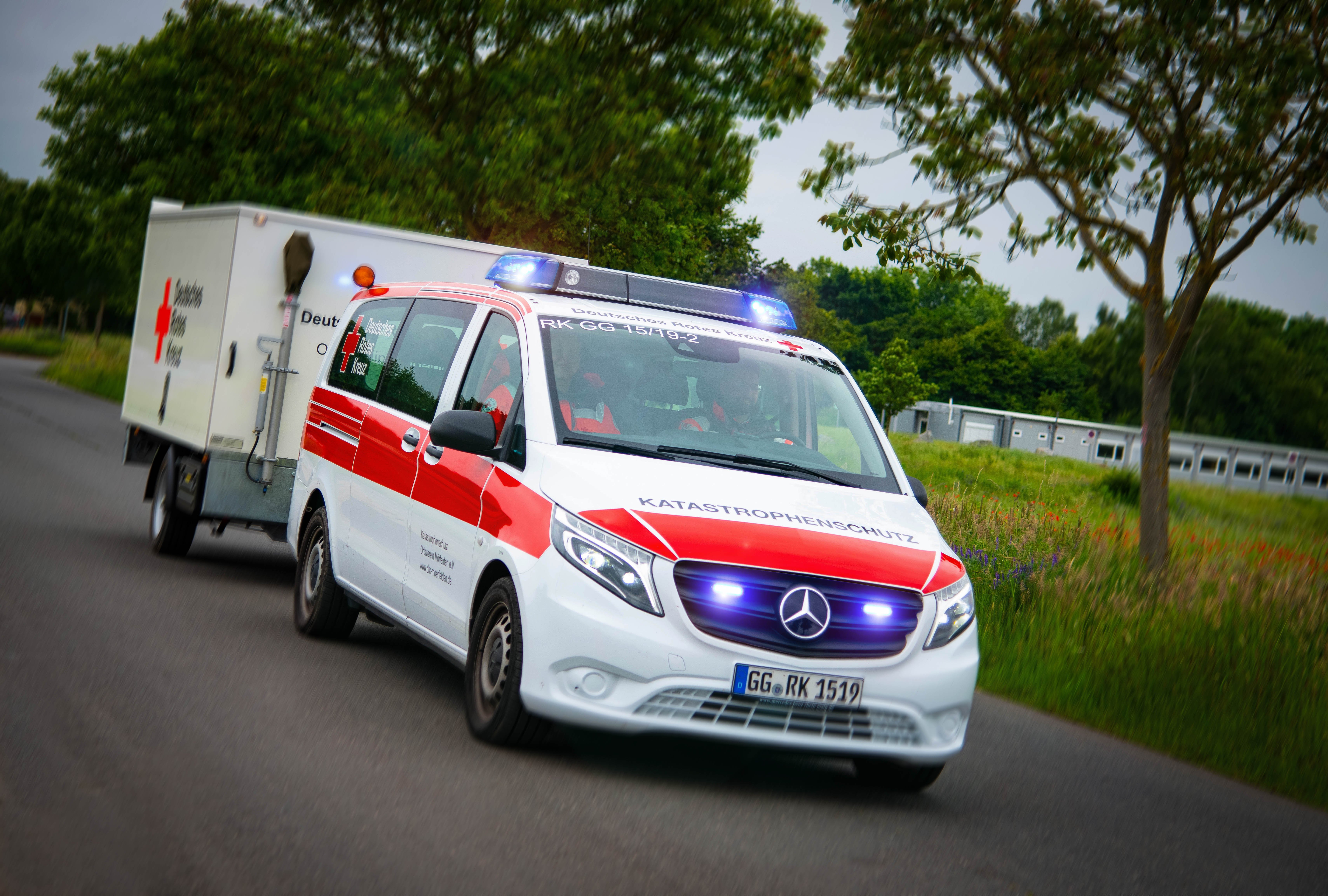 Einsatzwagen des Deutschen Roten Kreuzes mit Blaulicht und Anhänger.