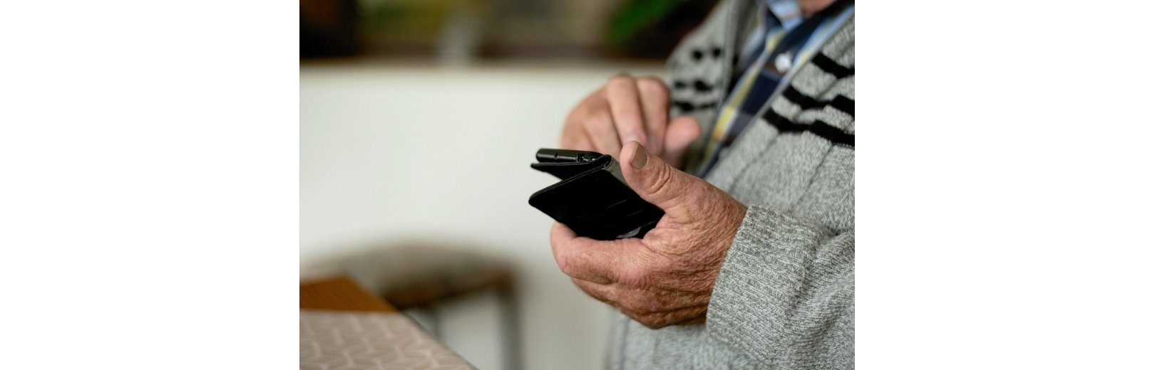 Man sieht die Hände eines älteren Menschen, der ein Smartphone hält.